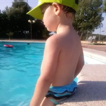 niño sentado en el borde de una piscina usando un bañador para incontinencia Absorvalia